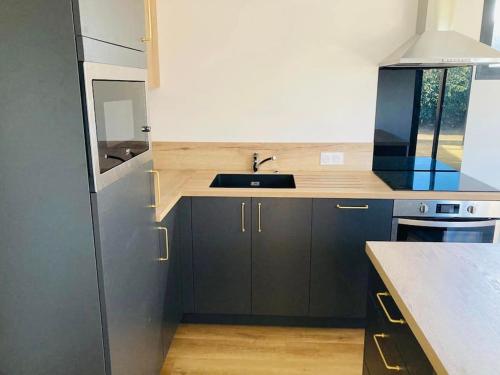 une cuisine avec un évier et un réfrigérateur dans l'établissement LA PARENTHESE DU GUILLEC, à Plougoulm