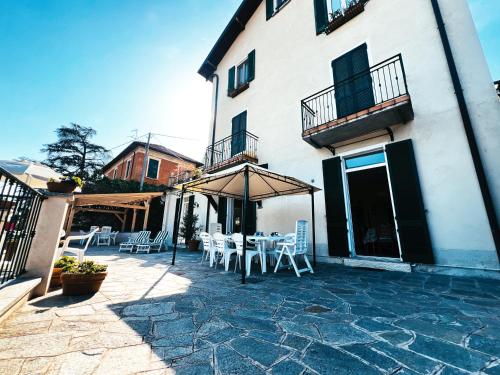 a patio with chairs and an umbrella in front of a building at Terrace Lake View Moltrasio in Moltrasio