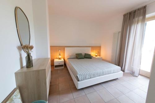 - une chambre blanche avec un lit et un miroir dans l'établissement Vistaverde Harmony Apartments, à Cavaion Veronese