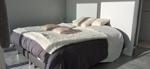 ein Bett mit einer Decke und Kissen darauf in der Unterkunft Chambre avec terrasse privative et vue mer in Hanvec