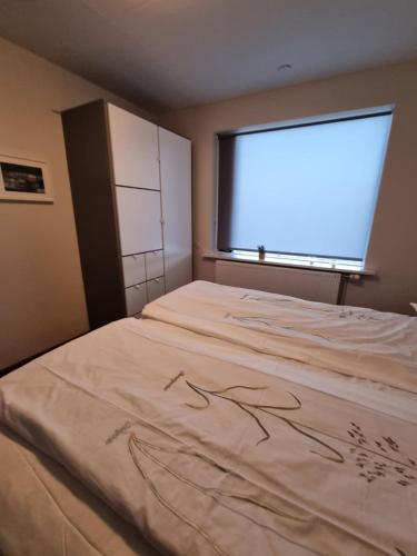 a bed in a room with a large window at Iceland-Aurora in Laugaras
