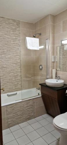 uma casa de banho com uma banheira, um lavatório e um WC. em Arnolds Hotel em Dunfanaghy
