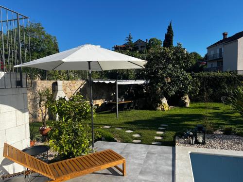 an umbrella and a bench in a yard at Meridiem Holiday Home in Dubrovnik region in Gruda