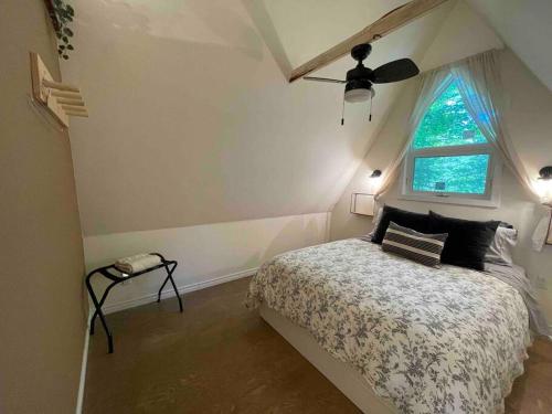 1 dormitorio con 1 cama, ventilador de techo y ventana en Cottage on the Noisy River Blue Mountain Wasaga, en Creemore