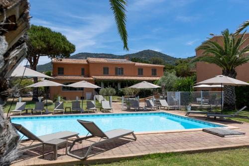 - une piscine avec des chaises et des parasols en face d'une maison dans l'établissement Villa Les Lentisques, à Cargèse