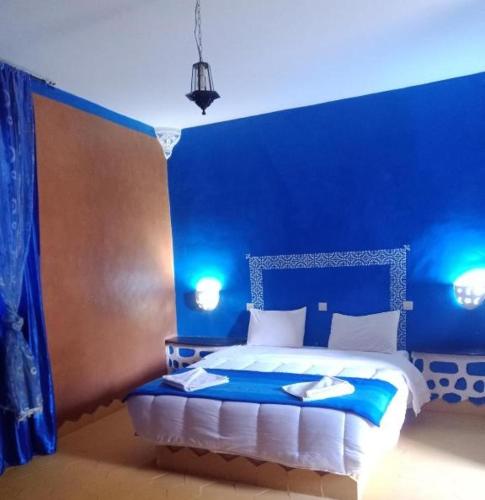 1 dormitorio azul con 1 cama con pared azul en AUBERGE DES ANGES, en Zrigat