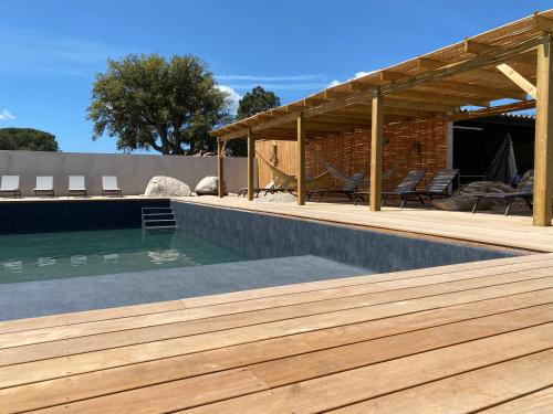 une piscine avec une terrasse en bois à côté d'une maison dans l'établissement Maison neuve Porto Vecchio, à Porto-Vecchio