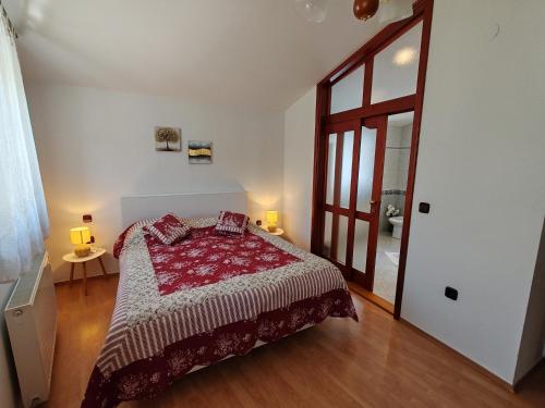 a bedroom with a bed with a red comforter at Apartments Kricin 14 in Baška
