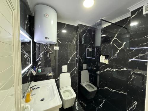 een badkamer met zwarte marmeren muren, een wastafel en toiletten bij Bamisa Apartments in Golem
