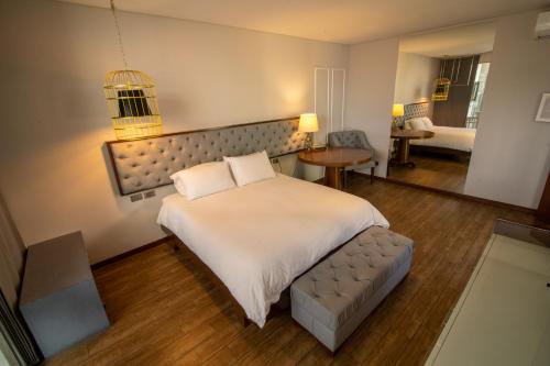 1 dormitorio con 1 cama blanca grande y 1 sofá en Cosmopolitano Hotel Boutique en Santa Cruz de la Sierra