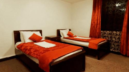 una camera d'albergo con due letti con lenzuola arancioni di Masaya Al Deyar Apartments ad Amman