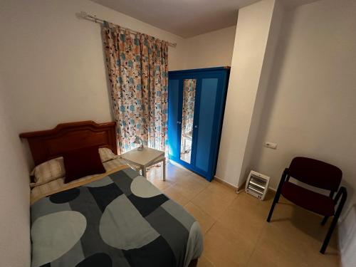 1 dormitorio con cama, ventana y silla en Casa Rural Familiar , Castilleja del Campo , Sevilla, en Sevilla