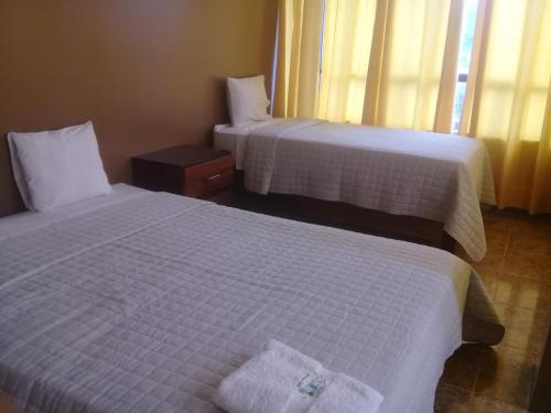 - 2 lits dans une chambre d'hôtel avec des draps blancs dans l'établissement Confort Pichanaki, à Pichanaki