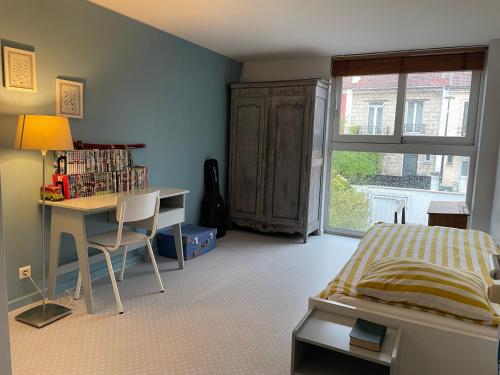 Schlafzimmer mit einem Bett, einem Schreibtisch, einem Bett und einem Fenster in der Unterkunft House & garden near Paris Arena in Vanves