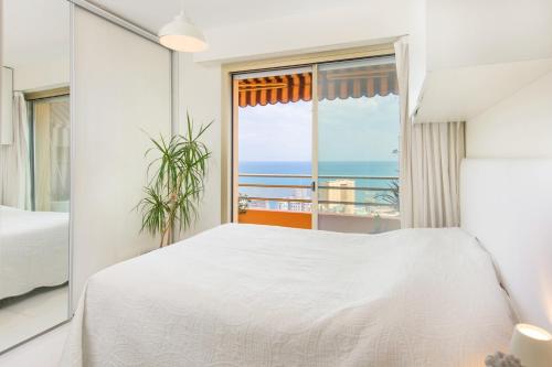 Schlafzimmer mit einem weißen Bett und Meerblick in der Unterkunft Luxueux 3 pièces - Frontière Monaco - Vue mer in Beausoleil