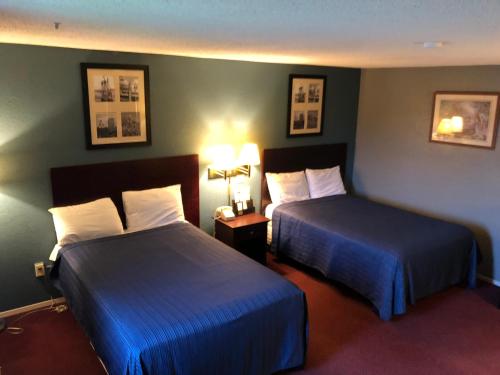 Habitación de hotel con 2 camas y 2 lámparas en Latham Inn, en Latham