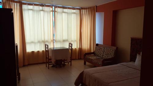 Habitación de hotel con cama, mesa y sillas en Confort Pichanaki, en Pichanaki