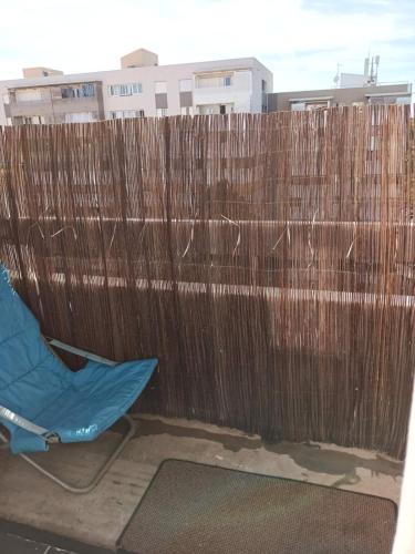 une clôture en bois avec une chaise bleue devant elle dans l'établissement Appartement F2, à Montpellier