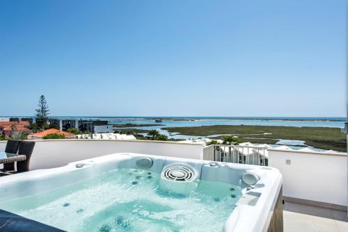 a bath tub on a balcony with a view of the ocean at 270 SQM - Pérola Da Fuseta - Pool & Jacuzzi - Terrace sea view in Fuzeta