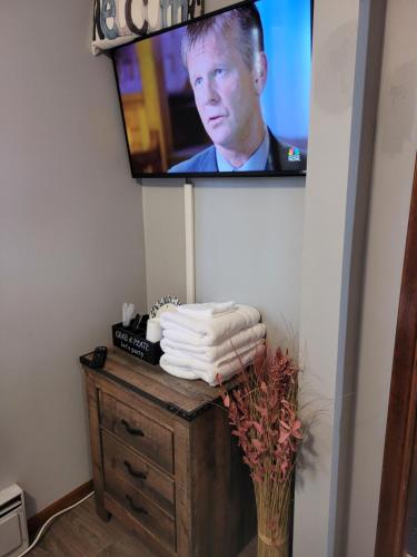 a tv on a wall with a table with towels at Compact But Cozy Too in Anchorage