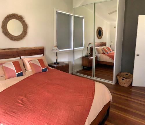 a bedroom with a large bed and a mirror at Cottage with Piano, Books & Games in the Hunter in Singleton