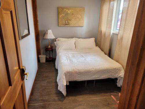 een kleine slaapkamer met een bed met witte lakens bij Compact But Cozy Too in Anchorage
