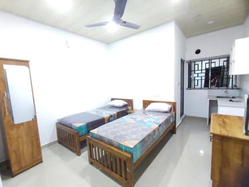 two beds in a room with a kitchen at Habees Residency in Chillithodu