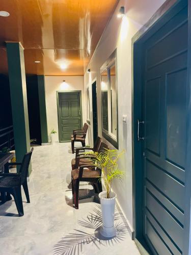 un porche con sillas, una puerta y una planta en Habees Residency en Chillithodu