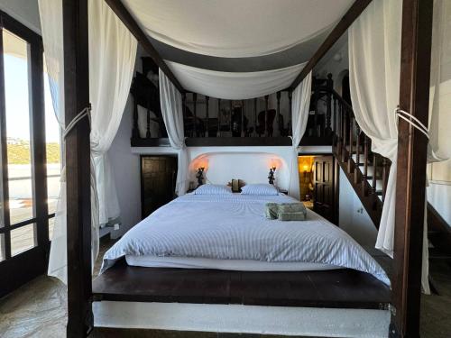 a bedroom with a canopy bed and a staircase at Hersonissos Andros in Gavrion