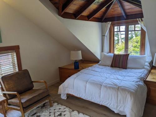 a bedroom with a king sized bed and a chair at Surfmen's Cottage - Historic Coast Guard property in Point Arena