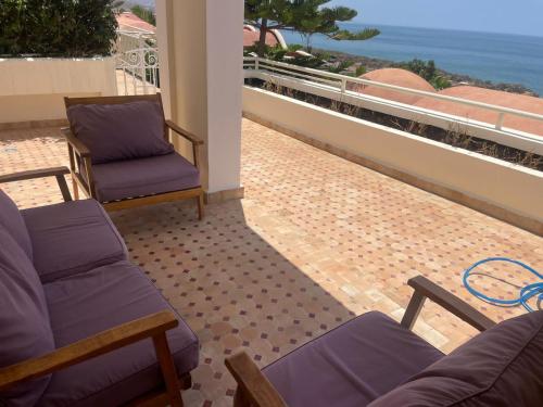 a patio with two chairs and a balcony with the ocean at résidence les meridiennes tiguert in Agadir