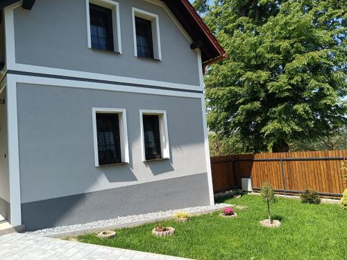 a white house with a yard with some plants at Chalupa pod hradom Branč in Podbranč