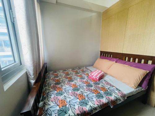 ein kleines Bett in einem Zimmer mit Fenster in der Unterkunft The Grass Residences in Manila