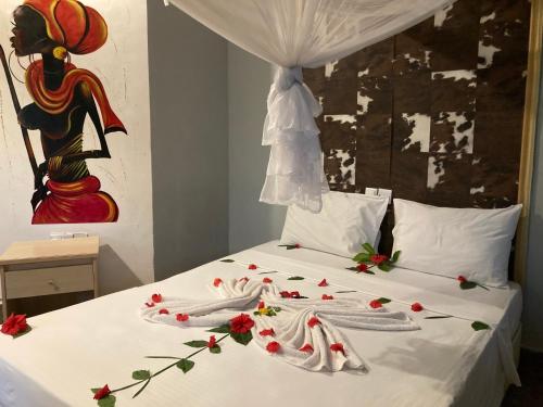 uma cama com lençóis brancos e flores vermelhas em PASA LODGE ZANZIBAR em Nungwi