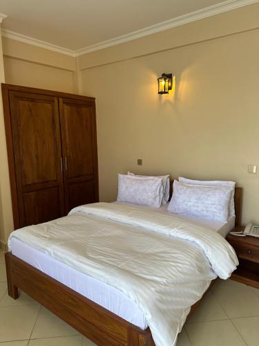 una camera da letto con un grande letto con lenzuola e cuscini bianchi di Aves Executive Hotel ad Arusha