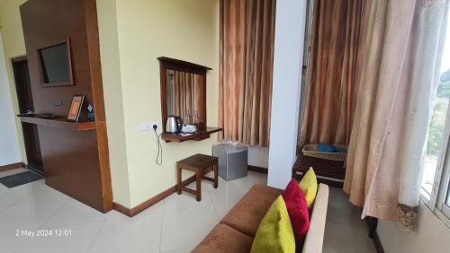 Una sala de estar con un sofá y un televisor y una ventana. en Quick Stop Inn, en Kandy