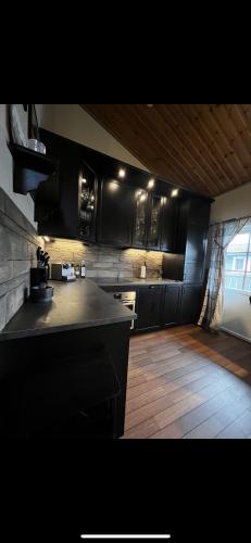 a kitchen with black cabinets and a wooden floor at Badstue, 3 soverom, nytt bad og kjøkken i Åre in Åre