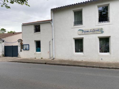 un bâtiment blanc sur le côté d'une rue dans l'établissement La Maison du Canal de Rompsay - 5 min de la Rochelle, à Périgny