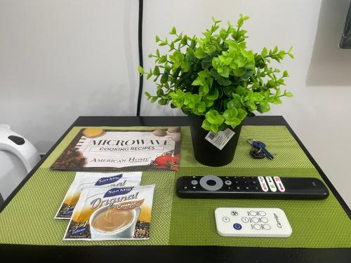 una tavola con telecomando, libri e una pianta di The Grass Residences a Manila