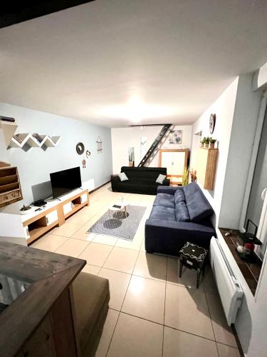 salon z niebieską kanapą i telewizorem w obiekcie Agréable maison de ville cosy de 122m² + extérieur w mieście Wattrelos