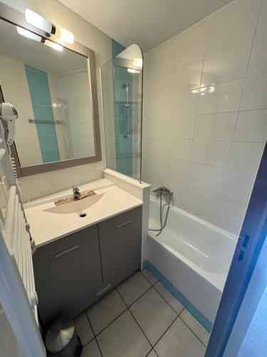 La salle de bains est pourvue d'un lavabo, d'une baignoire et d'un miroir. dans l'établissement Studio piscine proche plage et palais des festivals cannes banane, à Cannes
