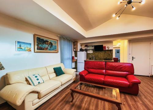 un salon avec un canapé rouge et une table dans l'établissement L'hirondelle, à Château-Thierry