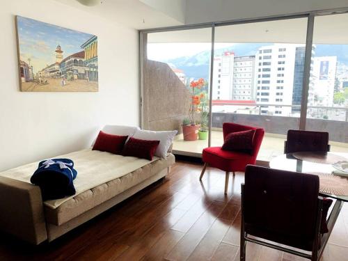 sala de estar con cama y ventana grande en Confortable departamento tipo loft, en Quito