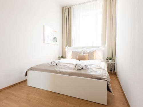 ein weißes Schlafzimmer mit einem großen Bett mit Handtüchern darauf in der Unterkunft Sage Apartment Old Town Bratislava in Bratislava