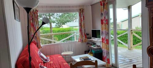 - une chambre avec un lit rouge et un balcon dans l'établissement Au Soleil Couchant - Camping Bel Sito Natura 2 000, à Surtainville