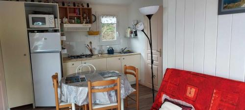 a small kitchen with a table and a refrigerator at Au Soleil Couchant - Camping Bel Sito Natura 2 000 in Surtainville