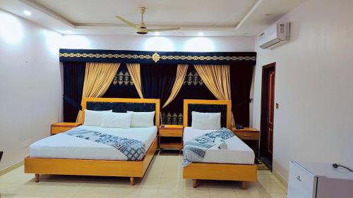 1 dormitorio con 2 camas y ventana en Clifton Lodge Boutique Hotel en Karachi