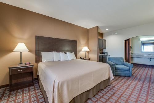 una habitación de hotel con una cama grande y una silla azul en Executive Inn & Suites Cushing, en Cushing