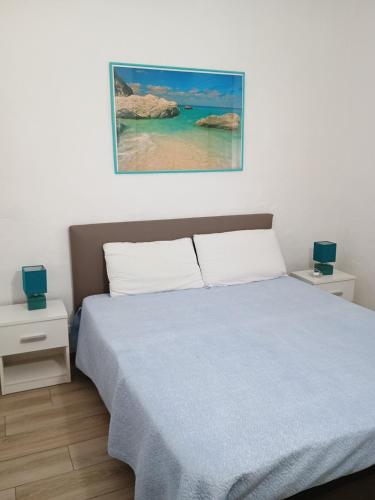 sypialnia z łóżkiem z niebieskim kocem i oceanem w obiekcie Villetta Bouganville w mieście San Teodoro