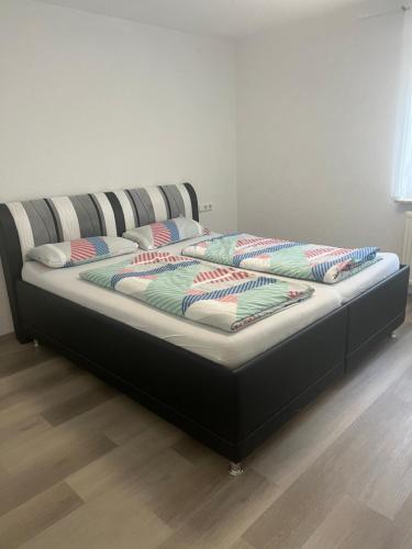 uma cama com uma moldura preta com almofadas em 4 Zimmer Ferienwohnung am Bodensee em Friedrichshafen